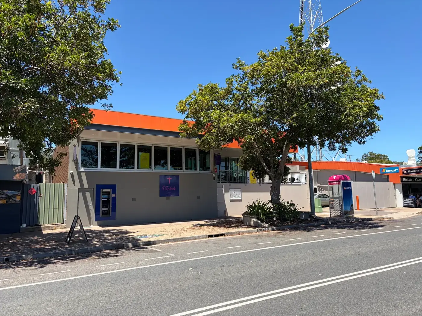 Supplied reference photo of the 9 Ballow Road frontage with orange fascia, street tree, ramp and neighbouring shops.
