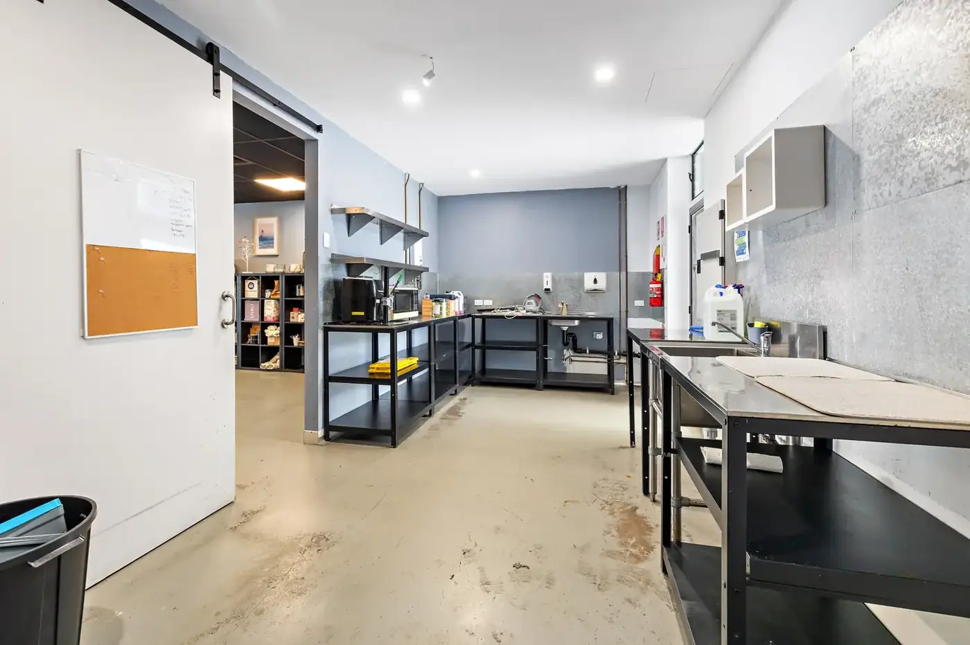Supplied reference photo of the wet area with stainless benches, sink, shelving and safety fixtures.